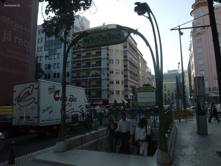 Entrée de métro signalée par une arche « Metropolitano » au milieu d’une rue urbaine.