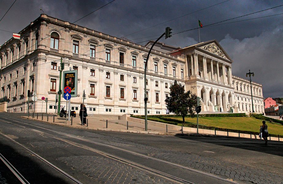 Vue extérieure du palais de São Bento, avec son entrée à colonnes et une rue au premier plan.
