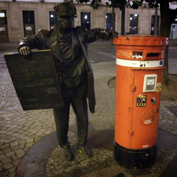 Statue du vendeur de journaux de Porto, appuyée sur une boîte aux lettres.