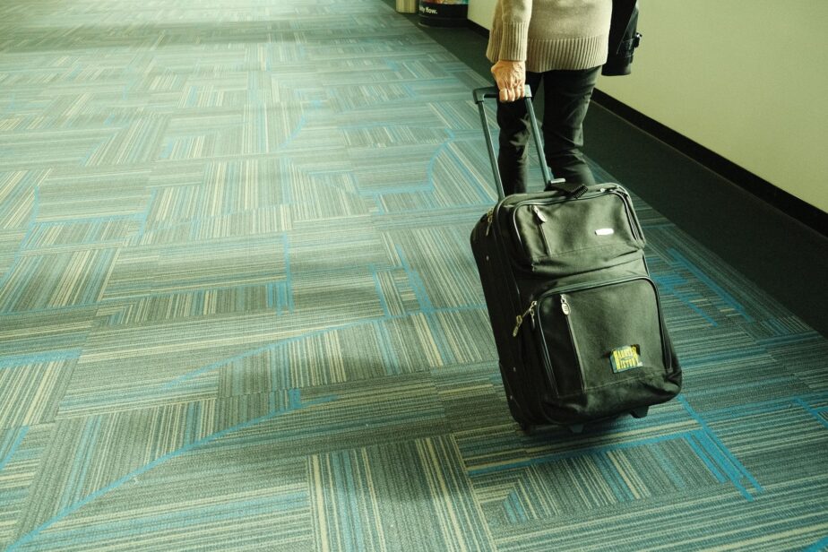 Une personne tire une valise dans un couloir d’aéroport.