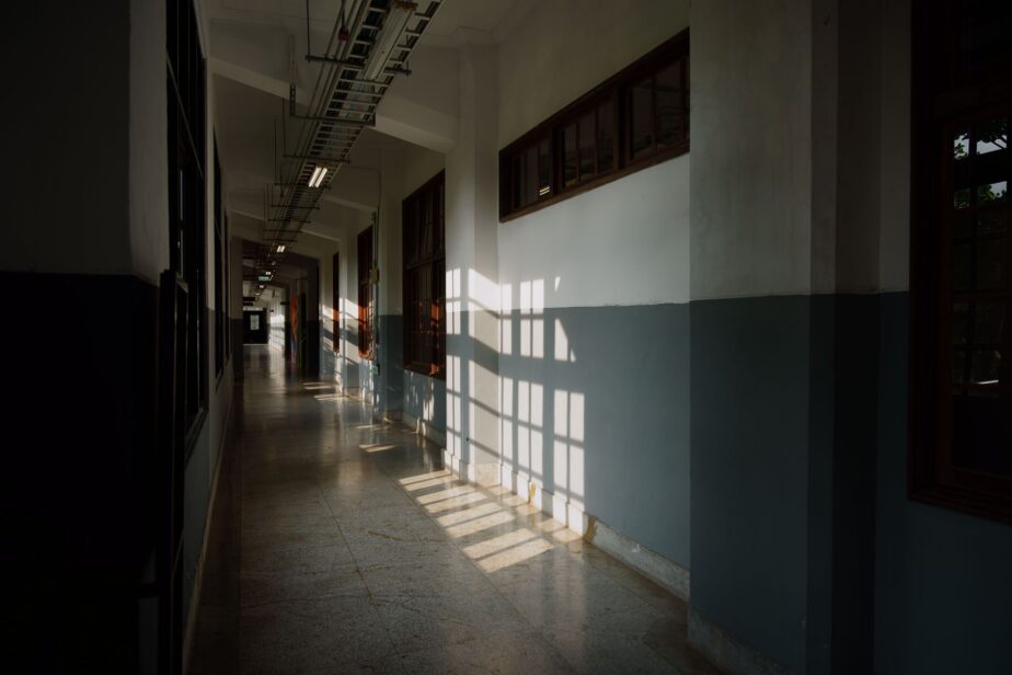 Un couloir intérieur vide, éclairé par le soleil, avec des portes de chaque côté.