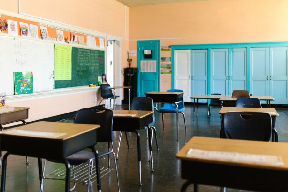 Une salle de classe vide avec des tables, des chaises et un tableau.
